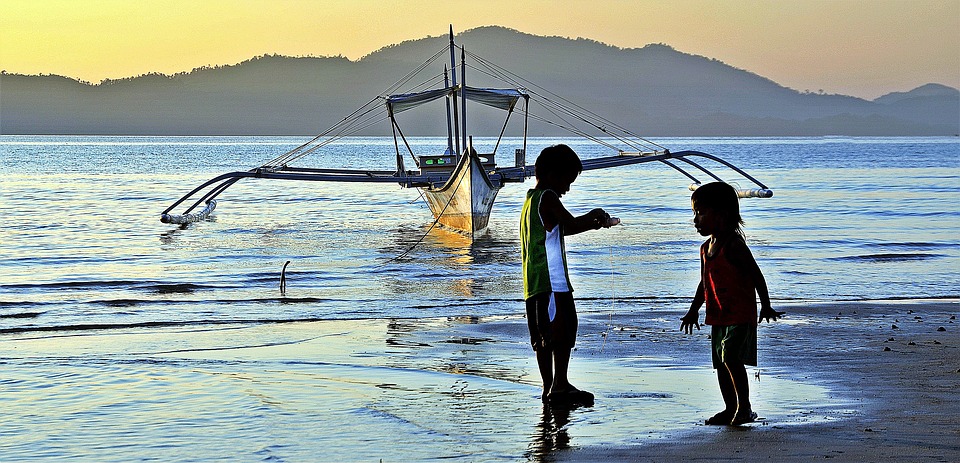 Kids playing beside a boat overlooking the sea