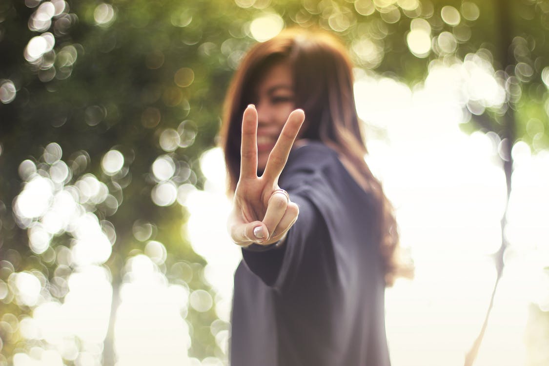 Smiling young lady with peace sign