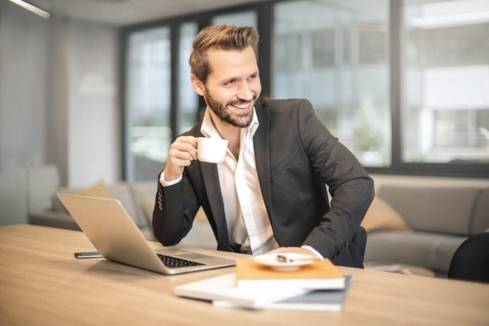 Man drinking coffee while working on his laptop