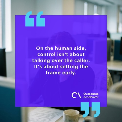 Contact-centre agent at a headset workstation listening intently to a caller with a soft I-hear-you hand gesture, not interrupting