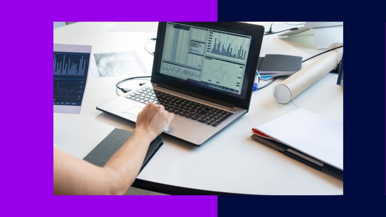 Investment firm employee working on CRM data cleansing on laptop with financial charts.