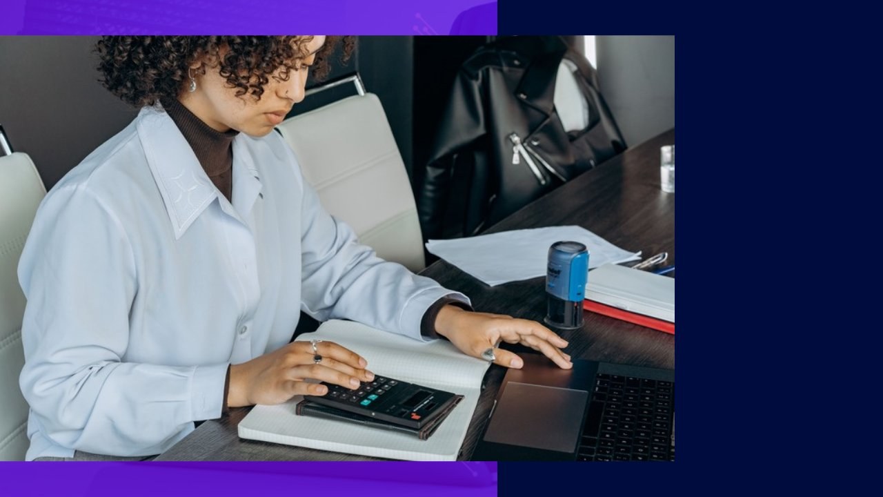 Person using calculator & laptop, considering outsourcing accounting tasks.