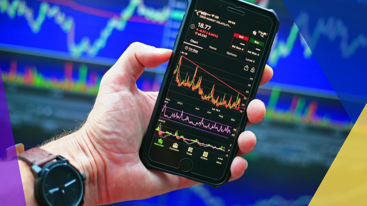 Hand holding a phone showing a declining stock chart against a wall of market data — the market says the billable hour is done