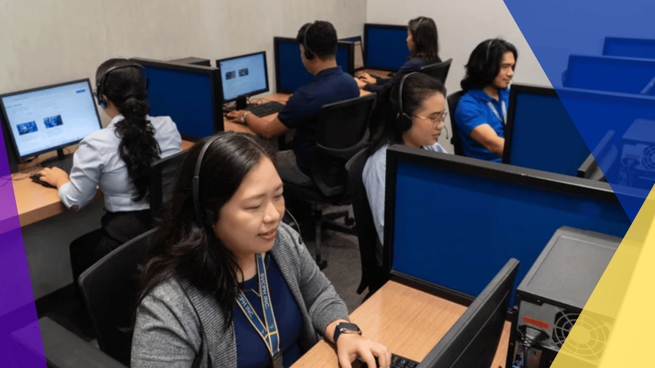 Call center agents in headsets at rows of dual-monitor workstations, a woman with a lanyard in the foreground, overhead office lighting.