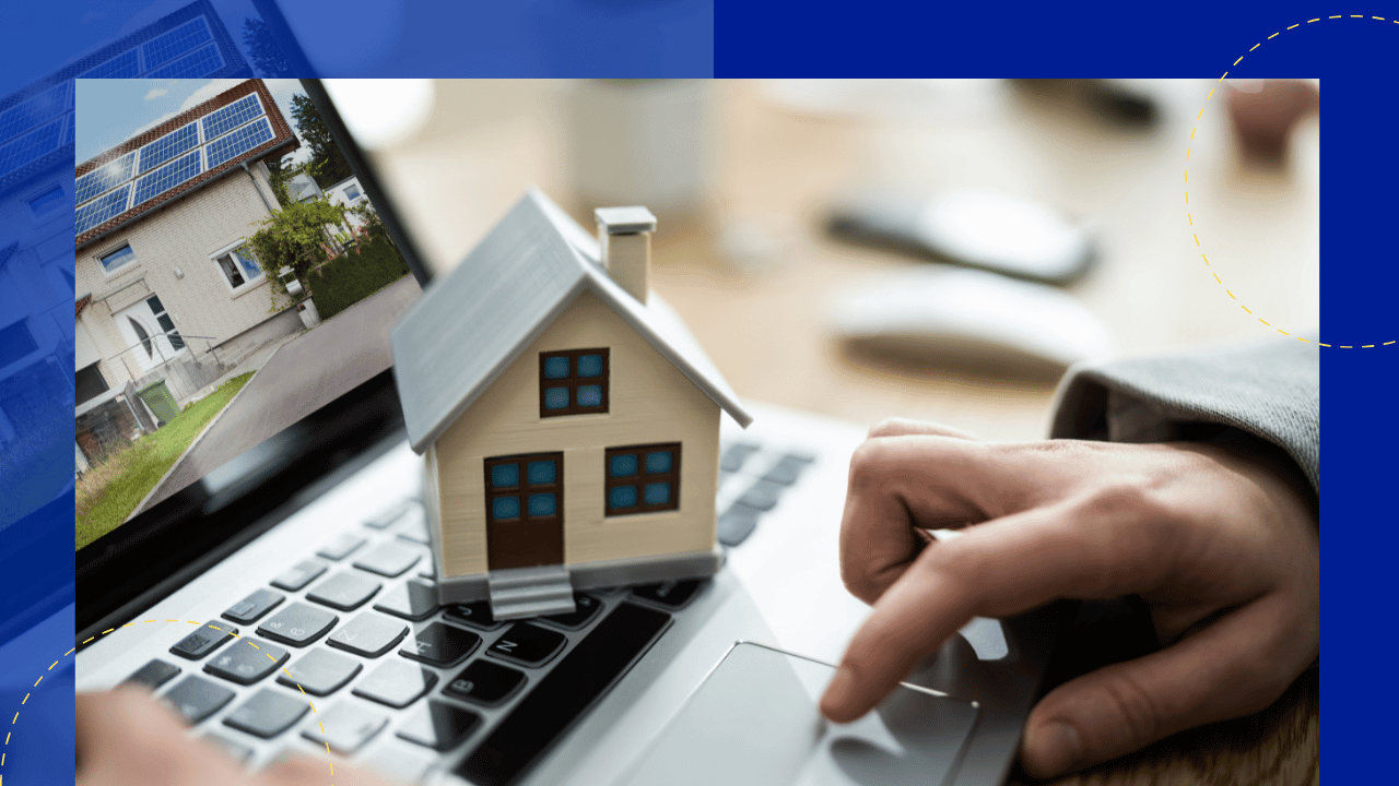 Hand on a laptop trackpad beside a small model house, screen showing a home with rooftop solar panels, soft indoor light.