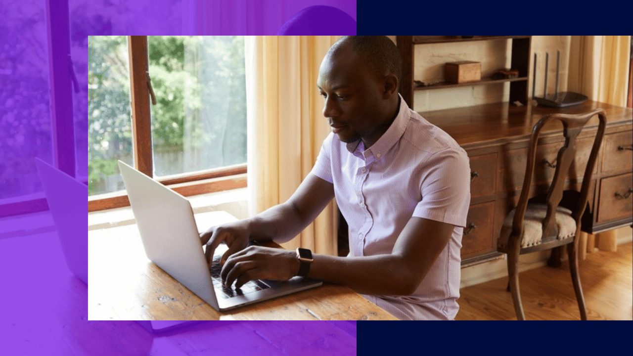remote performance management - remote employee typing on a laptop at a wooden desk at home
